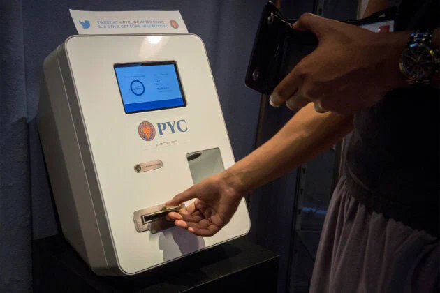 A customer feeds cash currency into a Bitcoin ATM located in Flat 128, a boutique in New York’s West Village, on Aug. 22, 2014.