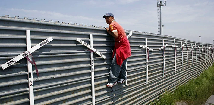 A migrant attempts to cross the US-Mexico border fence A migrant attempts to cross the US-Mexico border fence