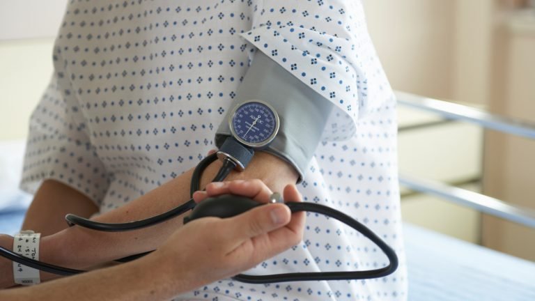 "Male doctor checking woman's blood pressure, mid section"